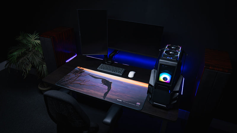 Wide view of the Raven America 250 deskmat in an RGB PC setup featuring a raven flying over Arches National Park sunset canyon scenery.