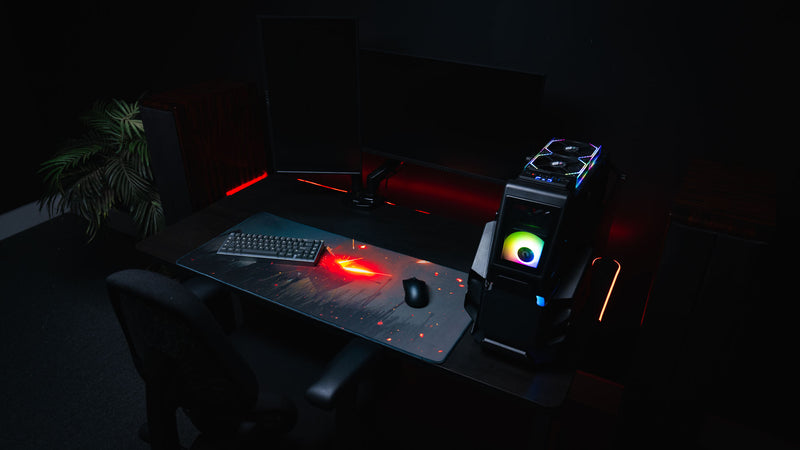 Ricochet deskmat featuring a fallen armored warrior with blazing fiery embers displayed on a modern RGB gaming desk with a mechanical keyboard, gaming mouse, and custom PC.