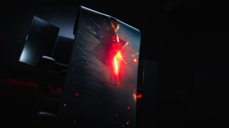Standing display of the Ricochet deskmat featuring a fallen armored warrior illuminated by blazing embers, showcasing the premium flexible construction and high-definition artwork.