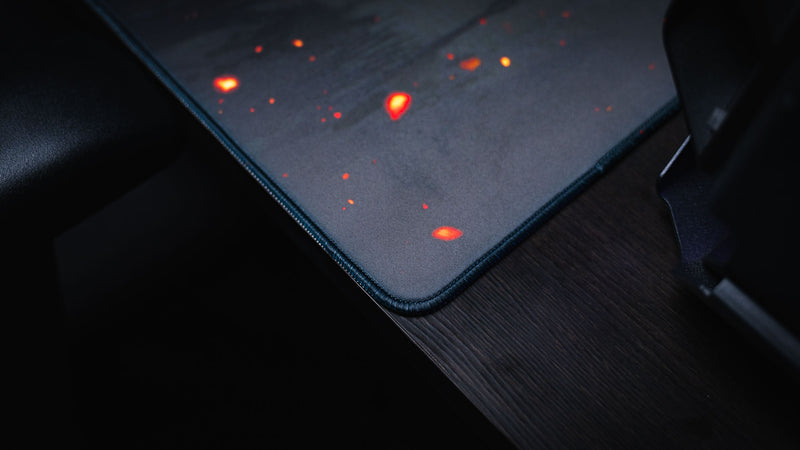 Close-up of the Ricochet gaming deskmat showcasing premium stitched edges, smooth cloth surface, and glowing ember details on the artwork.