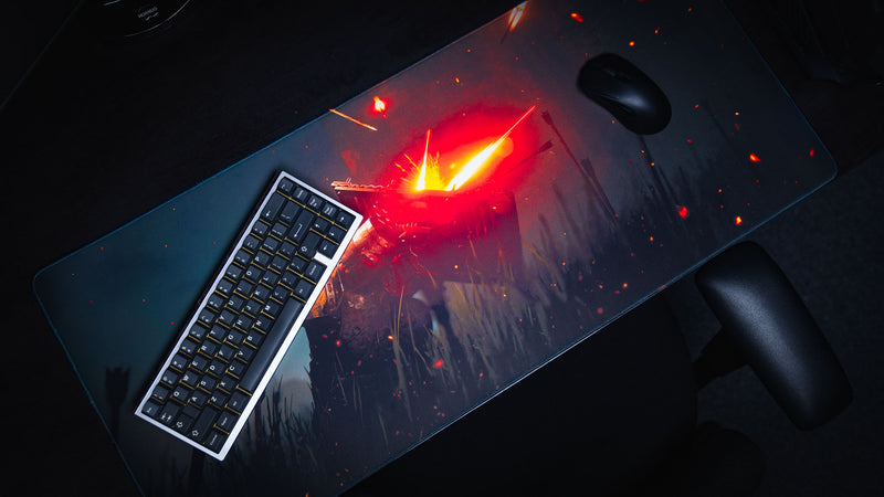 Angled view of the Ricochet deskmat featuring a fallen armored warrior illuminated by fiery sparks and glowing embers on a dark battlefield, displayed with a mechanical keyboard and gaming mouse.