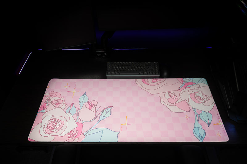 Front view of the Full Bloom desk mat on a dark desk, with roses framing the pink checkerboard.