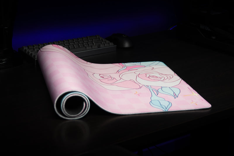 Rosy Racer's Full Bloom desk mat partially rolled on a desk, showing its floral print.