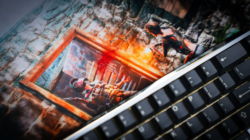 Close-up of The Doorcamper / Angle 1 Rust deskmat highlighting a dramatic firefight at a stone base entrance, with muzzle flashes and detailed artwork printed on a premium gaming deskmat.