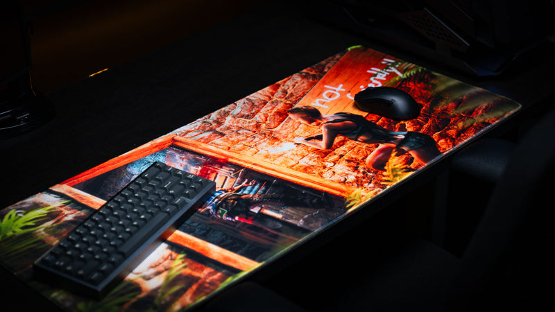 Angled view of The Doorcamper / Angle 3 Rust deskmat featuring a mechanical keyboard and gaming mouse, showcasing the detailed door raid artwork, stitched edges, and vibrant print quality.