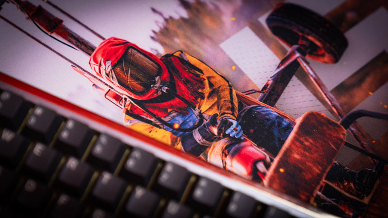 Close-up of a Rust helicopter pilot artwork gaming deskmat with cinematic lighting and mechanical details beside a keyboard.