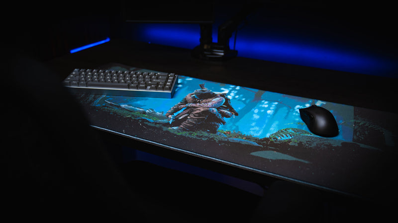 Official Rust Hunted XXL deskmat with a keyboard and gaming mouse, showcasing a lone survivor in a moonlit forest on a premium stitched-edge gaming deskmat.