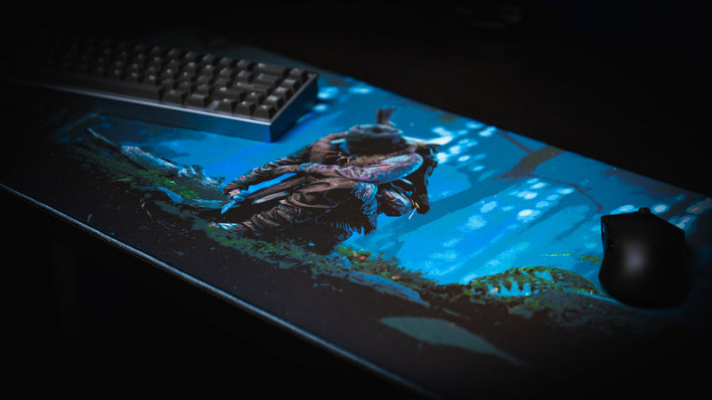 Official Rust Hunted XXL gaming deskmat with keyboard and mouse, featuring a lone survivor in a moonlit forest on a premium stitched-edge cloth surface.