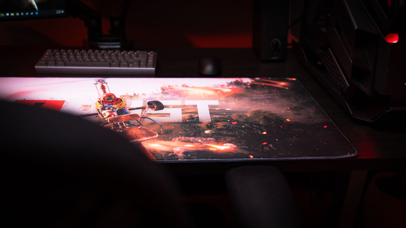 Dark gaming battlestation featuring the Rust “Minicopter Joyride” deskmat with cinematic minicopter artwork and fiery visual effects.