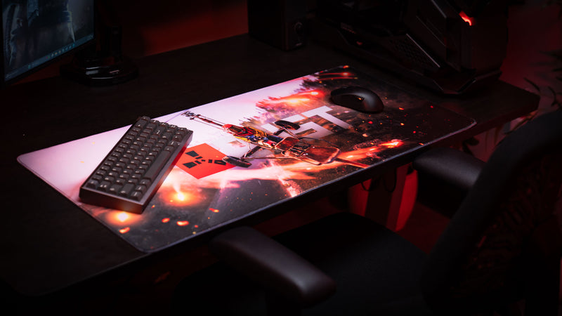 Premium gaming setup featuring the Rust “Minicopter Joyride” deskmat with explosive aerial artwork, compact keyboard, and gaming mouse.