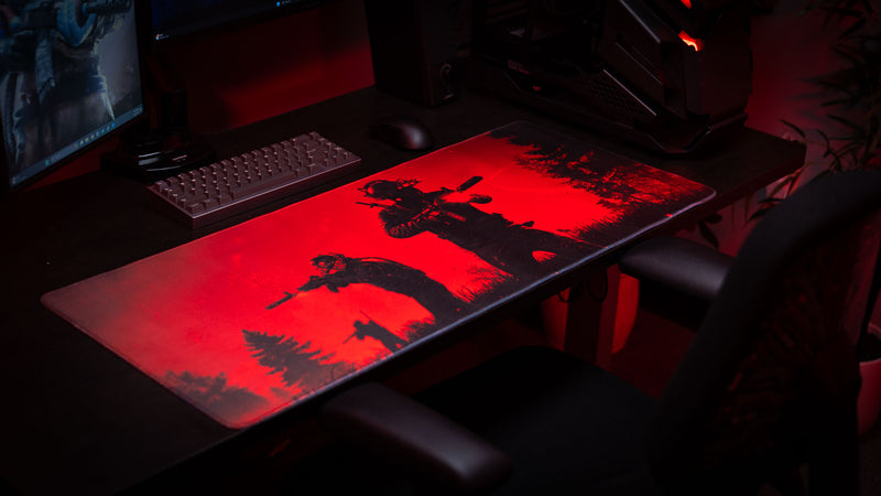 Nighttime Patrol Rust deskmat featuring a squad of armed survivors moving through a dark forest landscape silhouetted against a vivid red sky, displayed on a gaming desk setup.