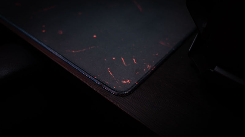Close-up of the Satellite Dish deskmat featuring stitched edges, textured surface detail, and dark red Rust-inspired artwork.