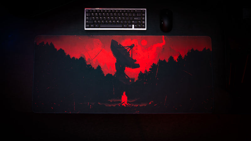 Satellite Dish XXL gaming deskmat displayed in a dark setup featuring a massive satellite dish silhouette, red sky, and atmospheric forest artwork inspired by Rust.