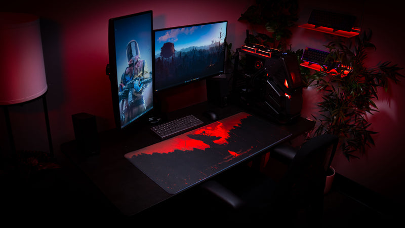 High-end gaming setup featuring the Satellite Dish XXL deskmat with red Rust-inspired artwork, dual monitors, red ambient lighting, and a custom gaming PC.