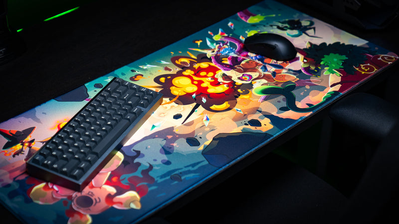 Angled view of the Sedi-mat deskmat by Pokedex Studios in a gaming setup, featuring an explosive fantasy creature battle, vivid colors, premium stitched edges, and smooth tracking surface.