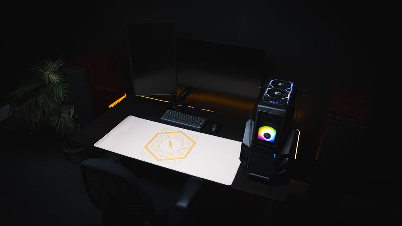 Feathered Host deskmat in a dark gaming setup with monitors and keyboard