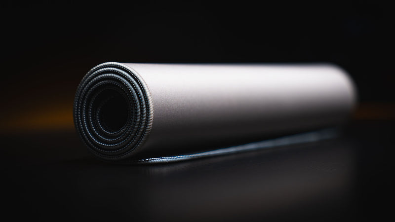 Rolled Feathered Host deskmat showing its fabric surface and stitched edge