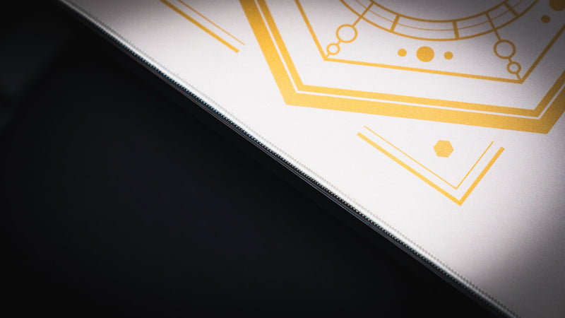 Close-up of the stitched edge and gold geometric design on the Feathered Host deskmat