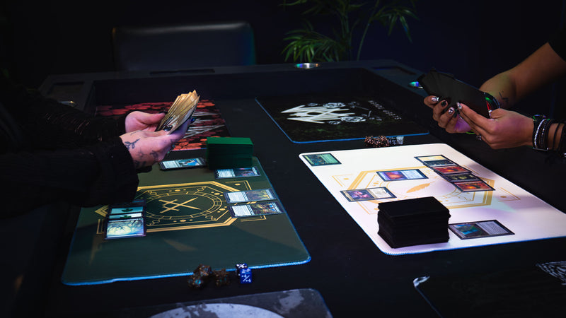 Two players using House Veridian and Feathered Host playmats during a trading card game