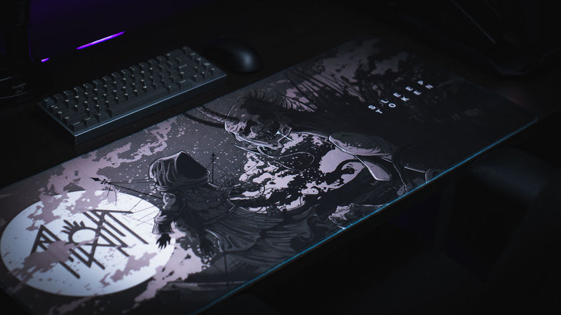 Angled view of The Battle deskmat showing the hooded figure facing the horned creature