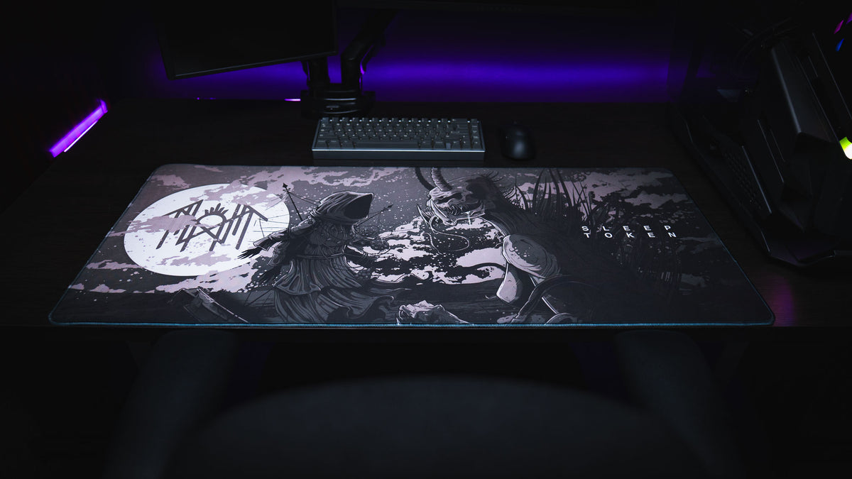 Front view of The Battle Sleep Token deskmat on a gaming desk with purple lighting