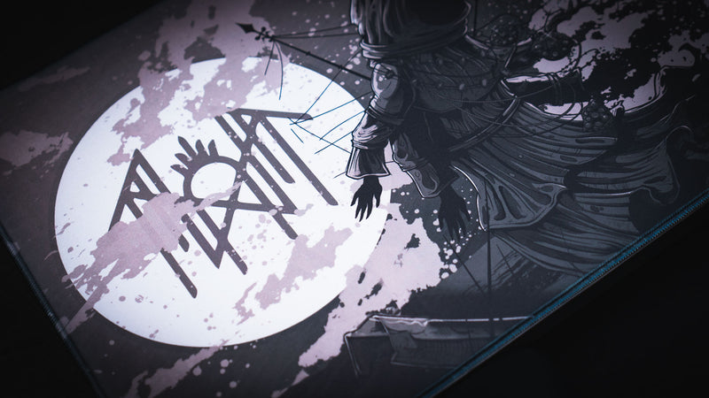 Close-up of the hooded figure beside the moon and sigil on The Battle deskmat