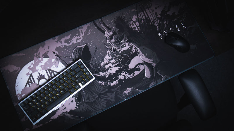 Overhead angled view of The Battle deskmat with keyboard and mouse across its monochrome artwork