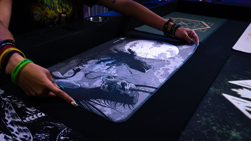 Player laying The Battle Sleep Token playmat on a gaming table, showing its moonlit design and blue edge