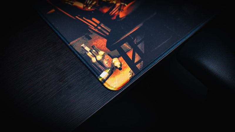 Close-up of the Sleight of Hand Rust gaming deskmat highlighting the premium stitched corner, cabin floor details, and poker night atmosphere.