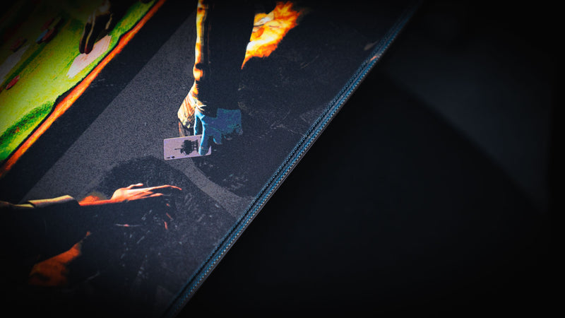 Close-up of the Sleight of Hand Rust gaming deskmat highlighting premium stitched edges, poker table artwork, and detailed cabin scene.