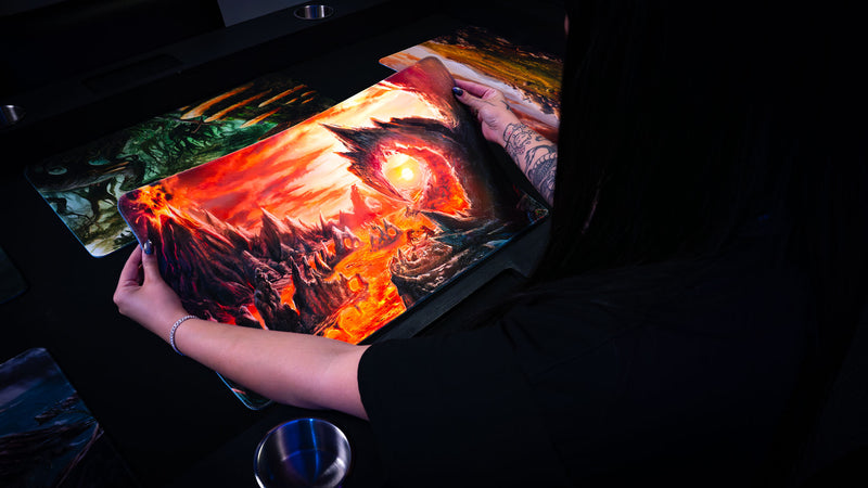 Person holding the Smoldering Mountain playmat, displaying its flexible construction and fiery volcanic fantasy artwork with glowing lava flows.