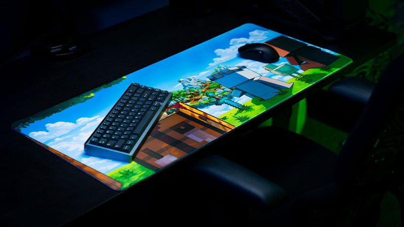 Angled desk setup featuring the Something Like That creator collaboration deskmat with colorful fantasy artwork, keyboard, and mouse.