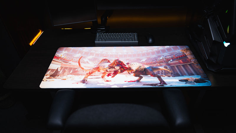 Full view of The Spinosaurus Chompers deskmat by Keenling featuring a brutal Spinosaurus and Triceratops battle inside a Roman gladiator arena, displayed on a gaming desk.