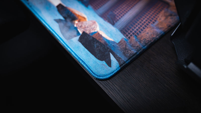 Close-up of The Spinosaurus Chompers deskmat by Keenling highlighting the premium stitched corner, durable edge, and detailed Roman gladiator arena artwork.
