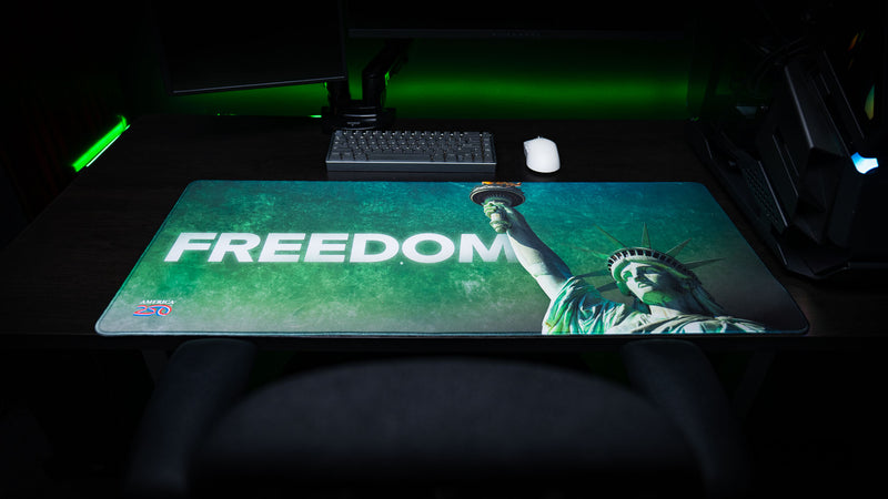 Statue of Liberty Freedom deskmat displayed on a gaming desk, featuring bold "FREEDOM" typography, Lady Liberty raising the torch, vibrant HD artwork, stitched edges, and an oversized extended mouse pad design.