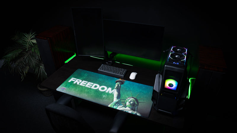 Statue of Liberty Freedom deskmat showcased on a modern gaming desk, featuring bold "FREEDOM" lettering, Lady Liberty with the raised torch, vibrant HD artwork, stitched edges, and an oversized extended mouse pad design.