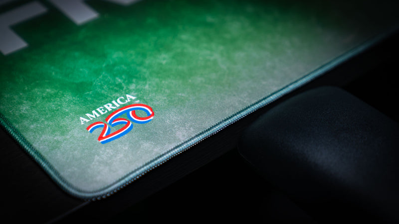 Close-up of the Statue of Liberty Freedom deskmat highlighting the America 250 logo, premium stitched edges, textured HD print, and durable extended gaming mouse pad construction.
