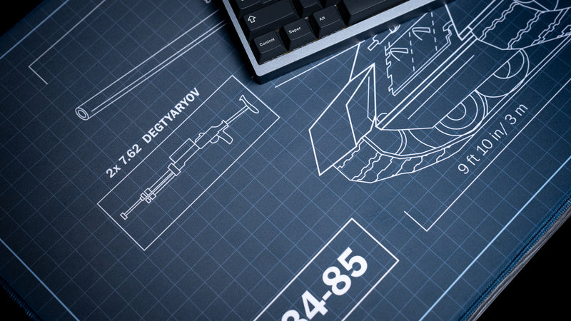 Close-up of the Jimarkus T-34 Schematic deskmat featuring the 7.62 Degtyaryov machine gun blueprint, T-34-85 tank schematic, and technical engineering grid design.