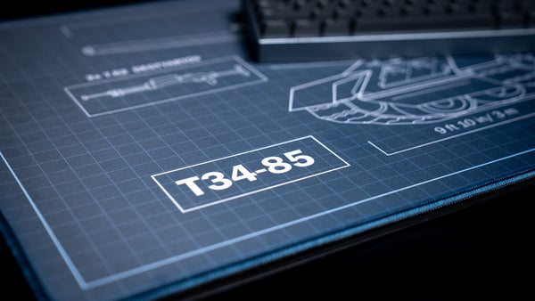Close-up of the Jimarkus T-34 Schematic deskmat featuring the T-34-85 title, technical blueprint grid, and detailed tank schematic with stitched edges.