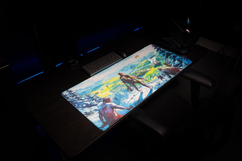 Right angled view of the Dead Horizon desk mat on a dark desk, with snowy pines and a vivid valley.