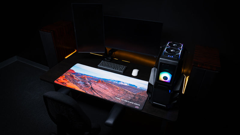 Trail to Delicate Arch deskmat displayed in a premium gaming desk setup, featuring panoramic Arches National Park photography with vivid HD print and stitched edges.