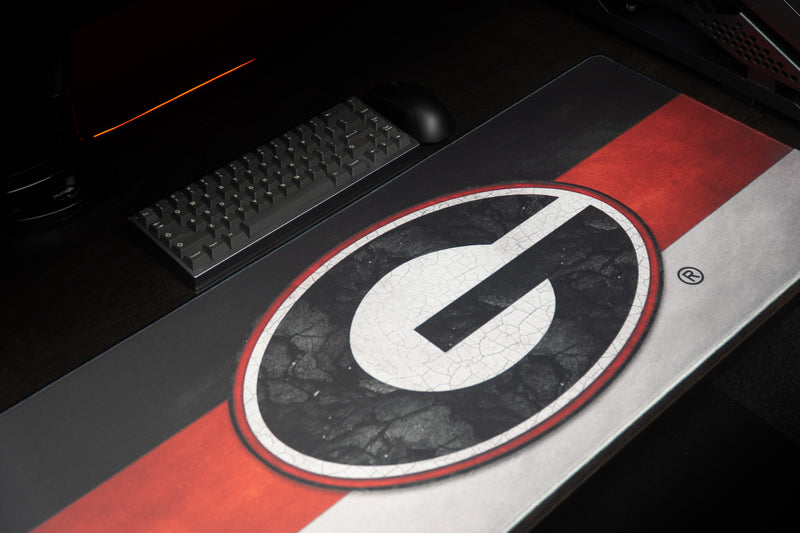 Angled close view of the Georgia Pride deskmat and centered G logo beside a keyboard.