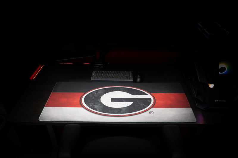 Front desk setup featuring the Georgia Pride deskmat with a white G over red and silver stripes.