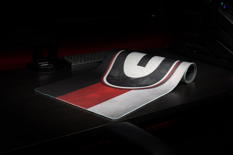 Georgia Pride deskmat partially rolled on a desk, showing the G logo and striped design.