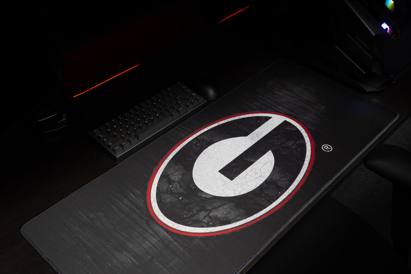 Close-up of the distressed white G logo with red outline on the Georgia Grit deskmat.