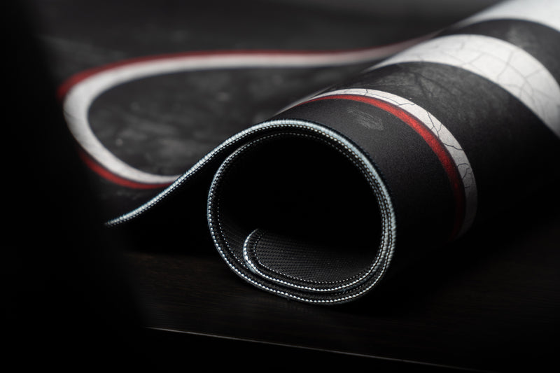 Close-up of the rolled Georgia Home Turf deskmat showing stitched edges and G design.