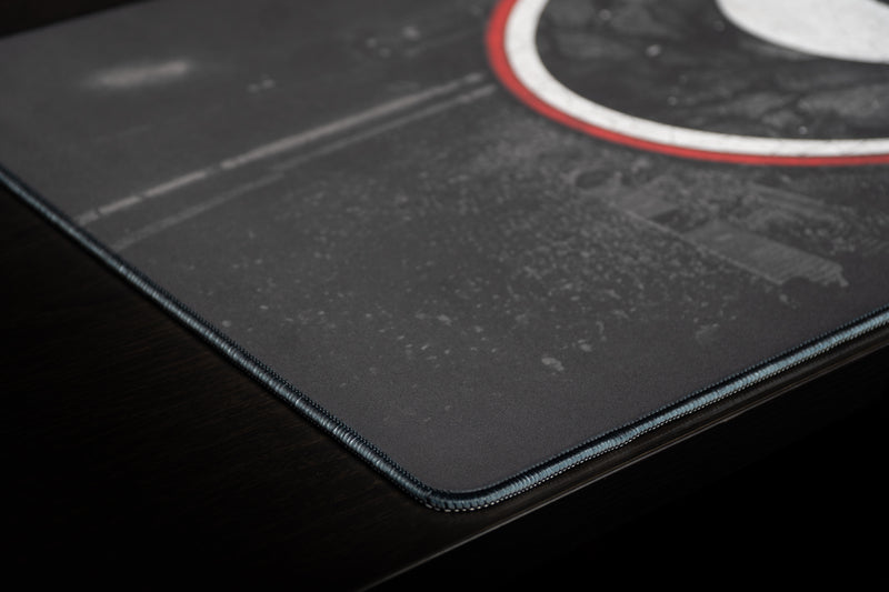 Close-up of the stitched edge and dark textured surface of the Georgia Home Turf deskmat.