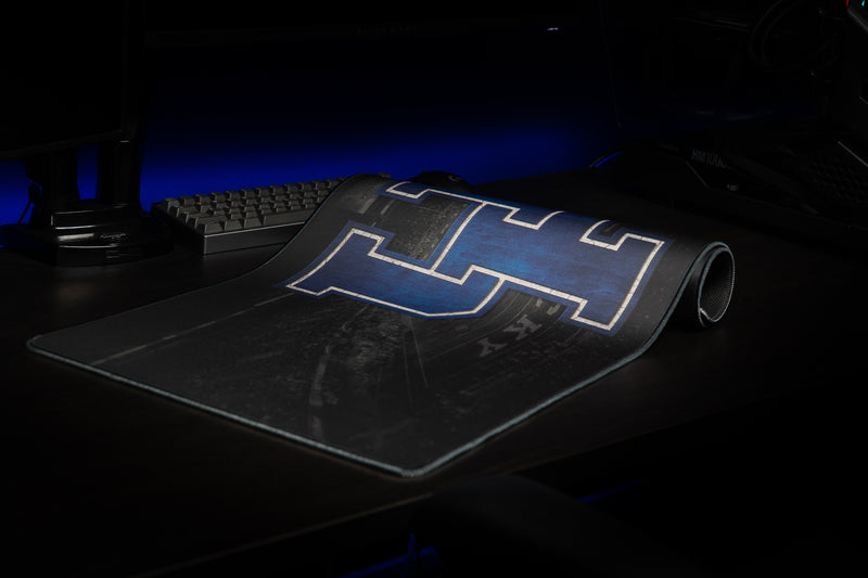 Kentucky Home Turf deskmat partly rolled, revealing its large blue UK logo and stadium design.