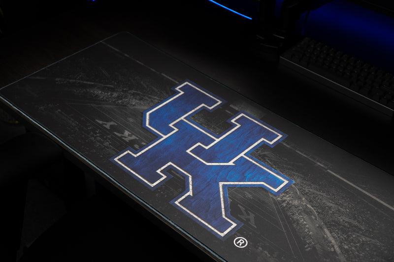 Angled close-up of the blue UK logo on the Kentucky Home Turf deskmat.