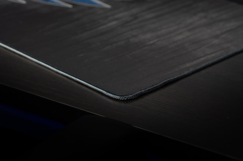 Close-up of the stitched corner and black textured surface of the Kentucky Mark of the Wildcat deskmat.